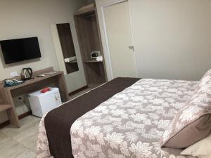 伊瓜苏港Ingá Apart & Suites的酒店客房,配有床和电视