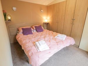 TarboltonMiddlemuir Retreat的一间卧室配有一张带粉色床单和紫色枕头的床