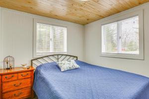 IronsCozy Wellston Cabin - Walk to Crystal Lake!的一间卧室设有蓝色的床和2个窗户。