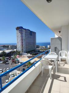 帕莱索海滩Olga Paraiso del Sur的阳台配有白色的椅子和桌子,大楼