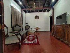 坎努尔Sukūn Heritage -A traditional 4 Bedroom Vacation Villa的客厅配有2把椅子和平面电视