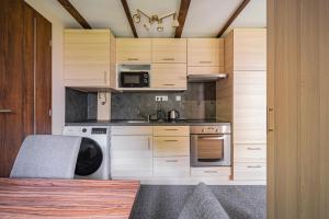 特勒克巴林特B48 Woodhause的厨房配有木制橱柜、水槽和炉灶。