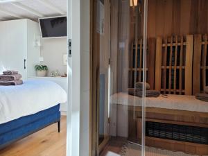 海边的艾格蒙特Tiny Villa de Haas met Infraroodsauna的一间卧室设有一张床和一个玻璃门
