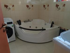 扎马迪NORA Guesthouse and Restaurant的浴室旁配有白色浴缸,旁边配有洗衣机