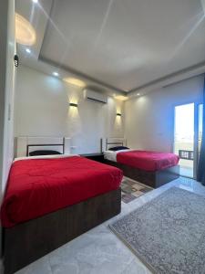 赫尔格达Al mashrabiya apartment 2 bed room的带窗户的客房内的两张红色床罩