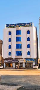 阿尔布亚米AL AMAN HOTEL的白色的大建筑,街道上设有蓝色窗户