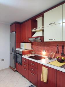 地拉那GEX Guest House的厨房配有红色橱柜和炉灶烤箱