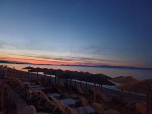 波利克罗诺Summer Beach Hotel的日落时分带椅子和遮阳伞的海滩