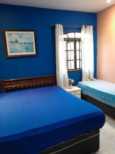 萨夸雷马Excelente casa em Saquarema a 100 passos do mar的一间蓝色卧室,配有两张床和窗户
