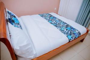 基加利Gmasters Homes kibagabaga的床上有蓝色和白色的毯子