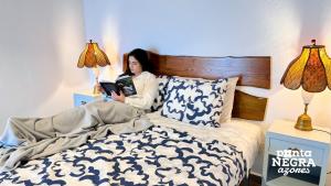 AltaresCharming Country House的躺在床上读书的女人