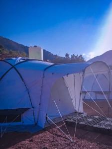 Luxury tent in the middle of nature的蓝白色的帐篷,后方是山