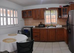 蓬塔卡纳Hostal Palmas De Punta Cana的厨房配有木制橱柜和一张带白色桌布的桌子。