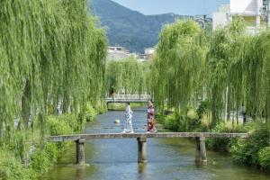 京都OMO5 Kyoto Sanjo by Hoshino Resorts的两个女人在河上过桥