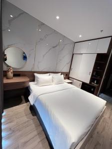 绥和市Apec Phú Yên SeaView Condotel的一张大白色的床,位于带镜子的房间里