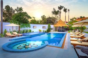 暹粒Sala Siem Reap Hotel的度假村的游泳池,配有椅子和遮阳伞