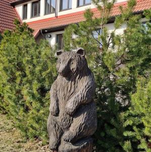 奥泰佩卡卢佩萨酒店的熊雕像,在一些灌木丛前