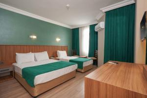 阿拉尼亚ERGÜN OTEL的绿墙旅馆客房的两张床