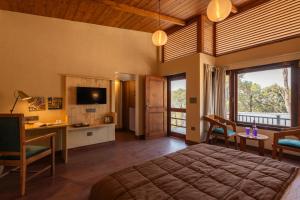 HawālbāghRudraa resort and restaurant的一间卧室配有一张床、一张书桌和一台电视。