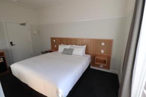 MortdaleMortdale Hotel的卧室配有白色大床和木制床头板