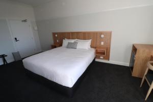 MortdaleMortdale Hotel的卧室配有一张白色大床和木制床头板