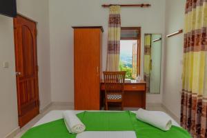 马特莱Siyonra Bungalow的一间卧室配有一张绿色的床、一张桌子和一把椅子