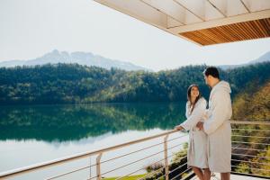 莱维科特尔梅杜拉克公园酒店的男人和女人站在一个俯瞰湖泊的阳台