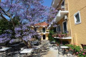 阿查拉维玛丽酒店的一座配有桌椅的建筑前的紫色树