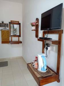 珍南海滩Chenang Indah Chalets的客房设有电视和带咖啡机的桌子。