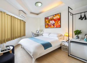胡志明市ELIOT HOTELs的卧室配有一张白色大床,墙上挂有绘画作品