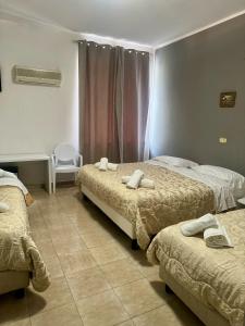 庞贝Hotel Il Santuario - Pompei的酒店客房,配有两张床和椅子