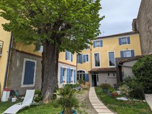阿杜尔河畔艾尔"Le Jardin sur l'Eau "chambres d'hôtes et appartement tout confort的黄色建筑前的树