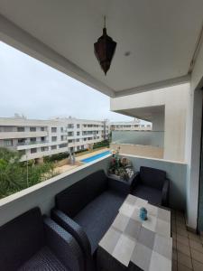 曼苏里亚Résidence Paradise Beach Aves piscine的阳台配有沙发和桌子,公寓大楼