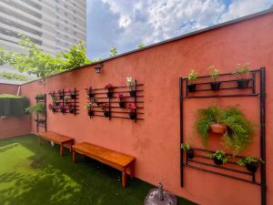 圣保罗Bistu Hotel - Vila Nova Conceição的墙上有长凳和盆栽植物