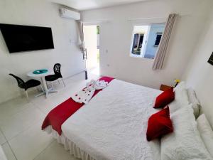 马拉戈日Pousada Peromar的卧室配有带红色枕头的大型白色床