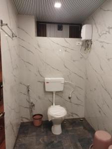 马泰兰Laxmi Hotel的白色大理石墙浴室设有卫生间