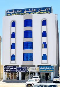 阿尔布亚米AL AMAN HOTEL的前面有汽车停放的建筑