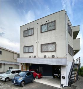 OzakiMy Home Inn Sennan, Onosato的两辆车停在停车场的大楼