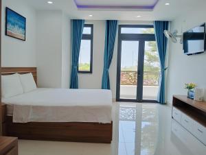 芽庄Thanh Hien villa的一间卧室配有一张带蓝色窗帘的床和一扇窗户