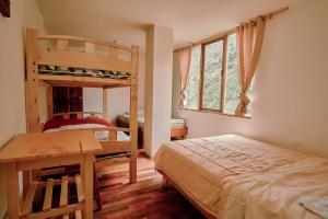 巴尼奥斯Backpackers-balcones-river-lodge的一间卧室配有两张双层床、一张桌子和一张书桌。