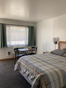 约翰迪John Day Motel的一间卧室配有一张床、一张桌子和一个窗户。