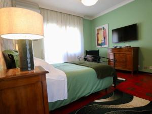 菲乌米奇诺Villa Gisi Guest House的一间卧室配有一张带灯具的床和一台电视
