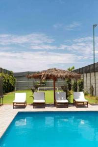 SunampeSOLARIUM CHINCHA Casa de Campo y Playa de 1000mts!的游泳池旁的两把椅子和一把遮阳伞