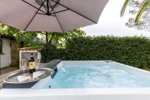 罗马Villa Del Rubbio的热水浴池,配有一瓶葡萄酒和一把雨伞