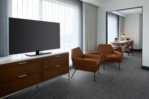 拉瓦尔Courtyard by Marriott Montreal Laval的酒店的客房配有平面电视和椅子。