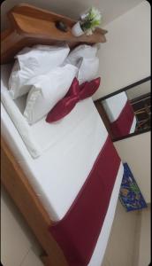 科托努Résidences Hôtel Perle Bleue的一张带红色和白色枕头的床和弓形领带