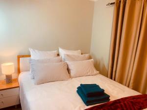 约翰内斯堡Afrikawisa@Rosebank的一张带白色枕头的床和蓝色毛巾