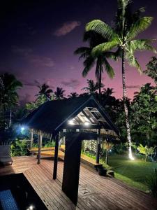 克罗托格Kaila Na Ua Resort的晚上在棕榈树甲板上摆放着一把黑伞