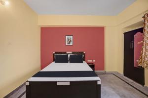 贾姆谢德布尔OYO 27 DEGREE HOTEL的一间卧室配有一张红色墙壁的床