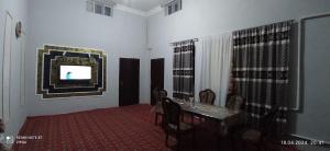 希瓦Khiva Saodat Guest House的一间设有桌子的用餐室和墙上的电视